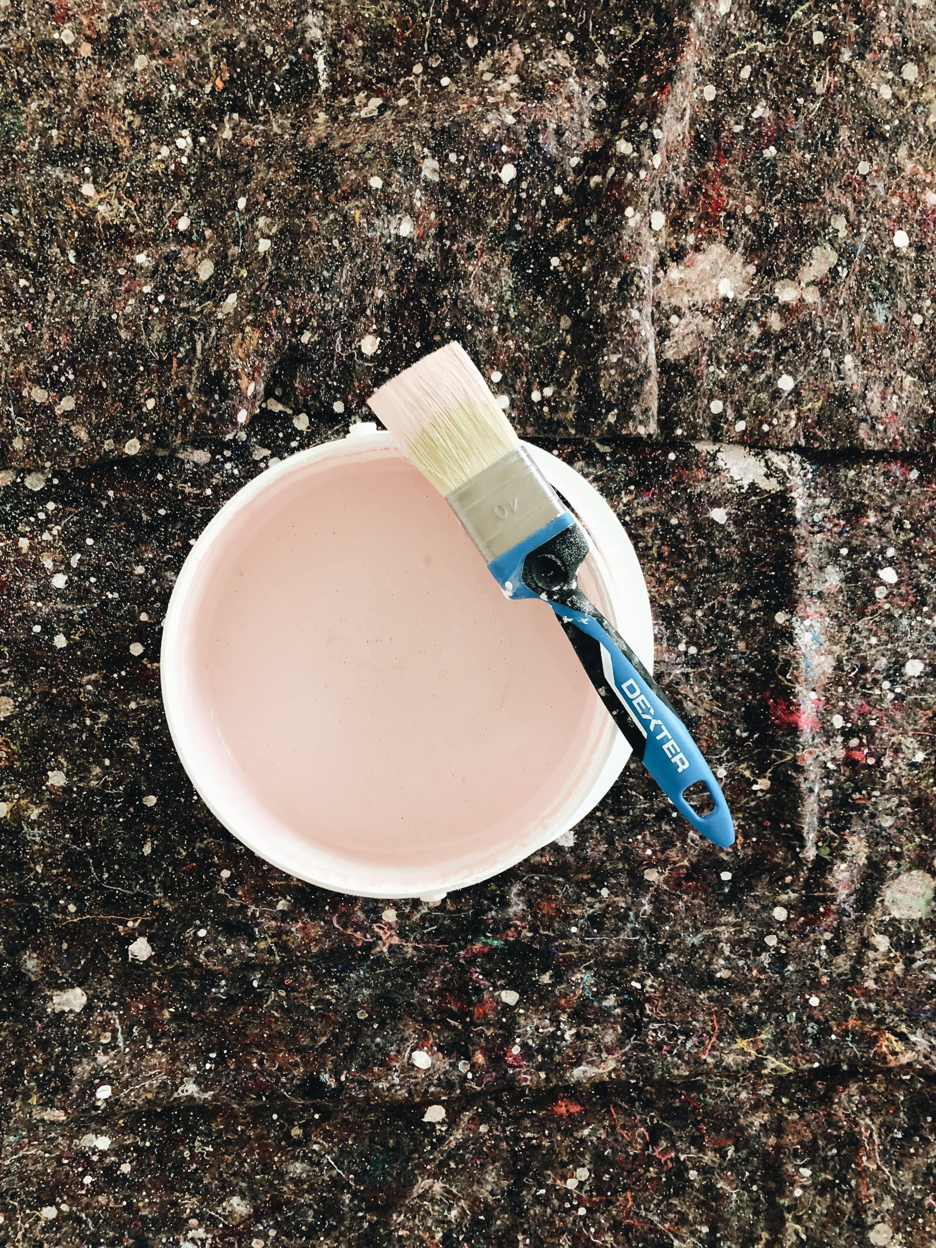 a paintbrush sitting in a white bowl on the ground